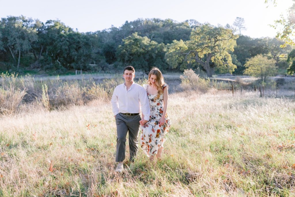 Engaged couple walking in a field in Santa Barbara