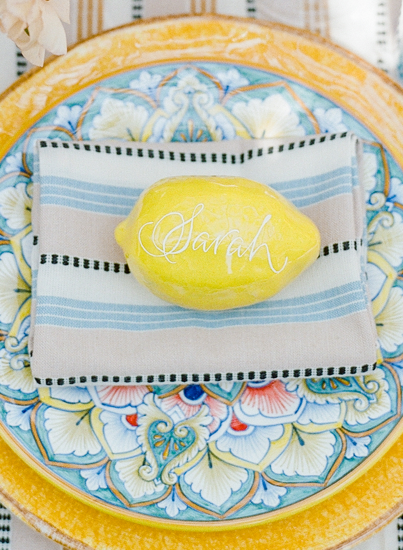 The name "Sara" written in calligraphy on a lemon for a place setting. 