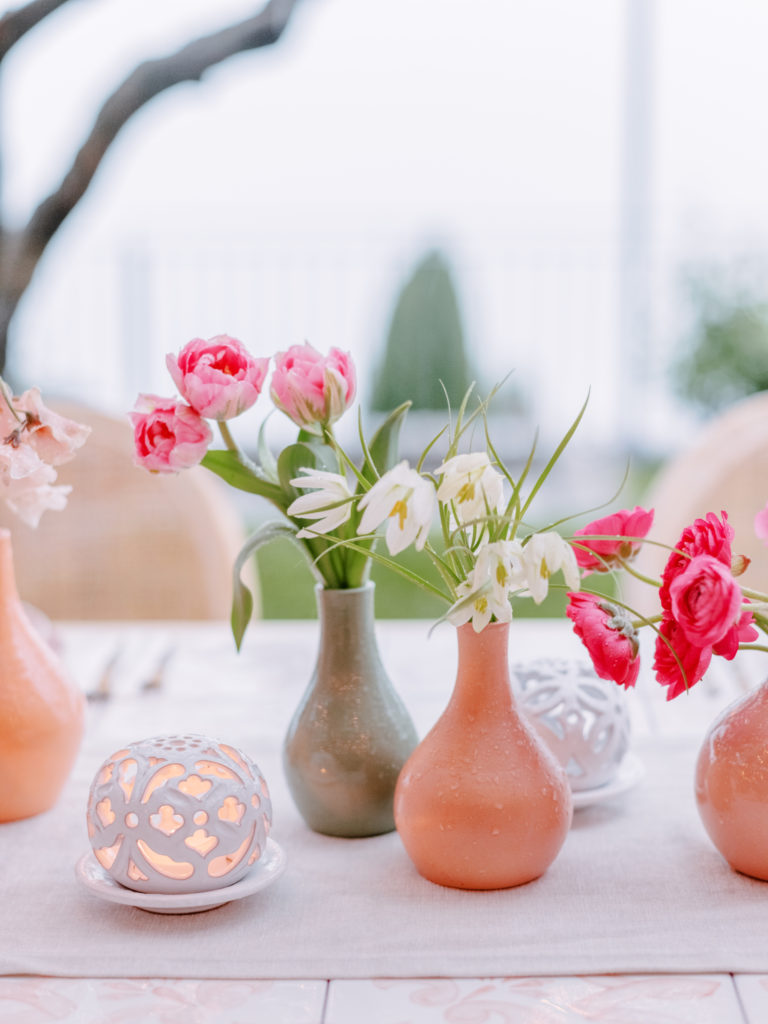 flowers in vases with a small tea white light next to it