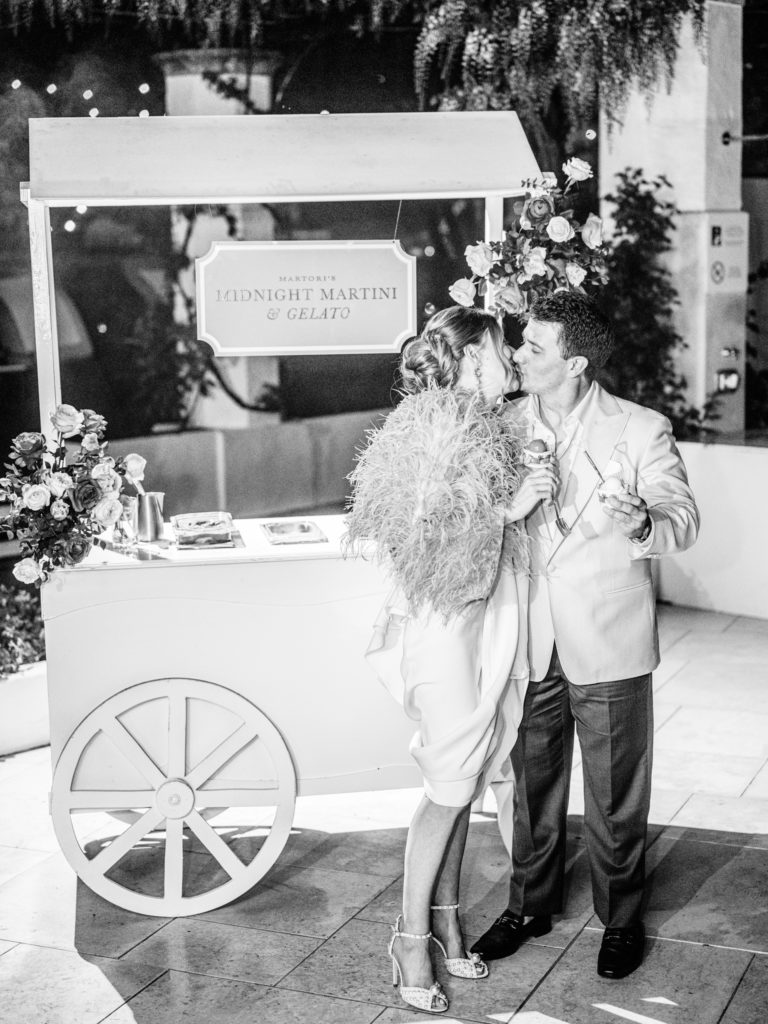 Couple kissing at their Rehearsal dinner while holding gelato